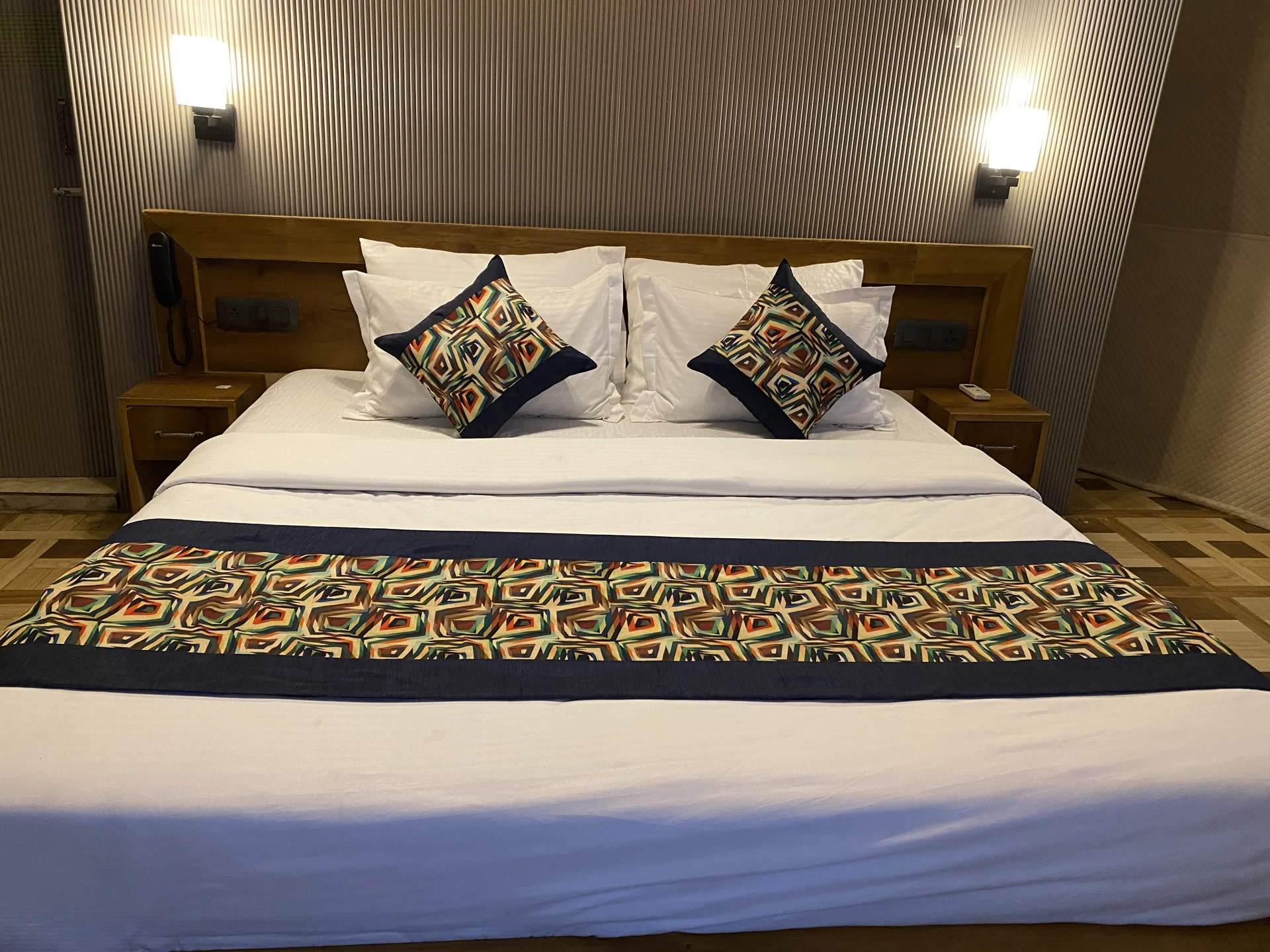 Resort bedroom with a wooden headboard and patterned bed linen